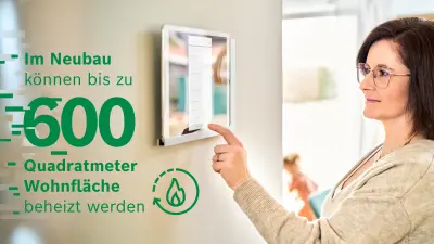 Melanie Wingerter steht vor dem Tablet, über das sich die Erdwärmepumpe regulieren lässt, und blickt in Richtung Kamera.