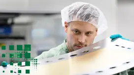 Person mit Haarnetz und Handschuhen hält Material für den Stack-Aufbau.