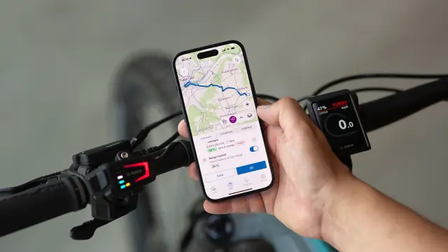 Person hält ein Smartphone mit einer Karten-App, während sie auf einem Fahrrad sitzt.