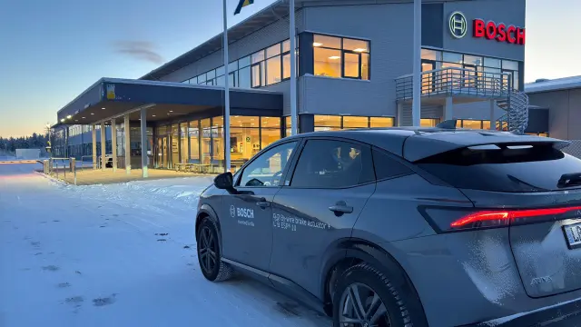 Test vehicle with brake-by-wire labeling parked in front of a Bosch building in winter.