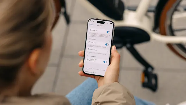 Smartphone displaying eBike lock settings held near a parked bicycle.