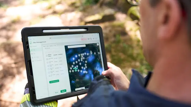 Tablet showing site management map interface used outdoors.