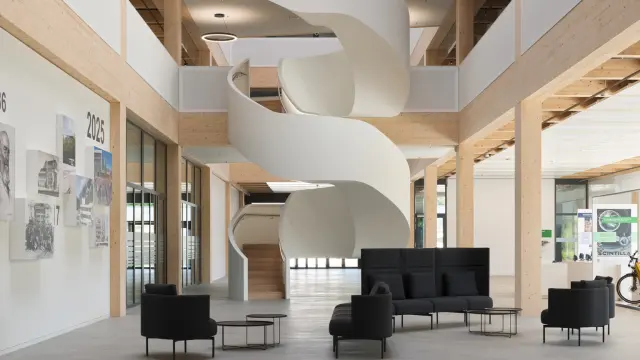 Interior of a modern building with wooden structure and a white spiral staircase.