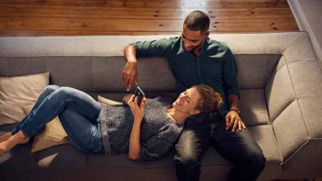 Ein Pärchen liegt gemütlich auf der Couch in Ihrem Haus, das mit Bosch Smart Home Technik ausgestattet ist. 