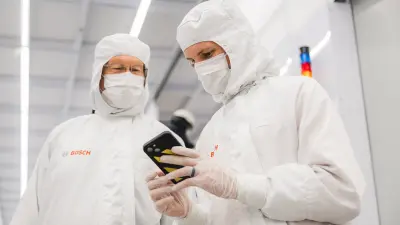 Two people in a cleanroom look at a smartphone