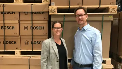Eine Frau und ein Mann stehen vor Paletten mit Bosch-Logo und lächeln in die Kamera.