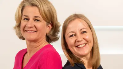 Zwei Frauen lächeln in die Kamera.