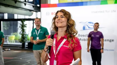 Ann-Katrin wears a pink polo shirt and holds a microphone, speaking at a Bosch event.