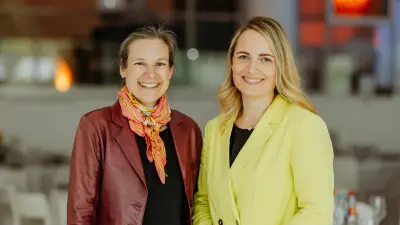 Anita and Judith pose smiling in colorful blazers in a modern, bright interior.