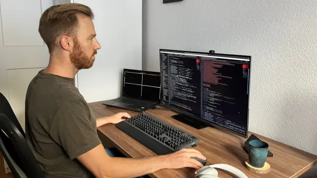 Ein Mann sitzt an einem Schreibtisch und blickt auf den Computer-Bildschirm. 