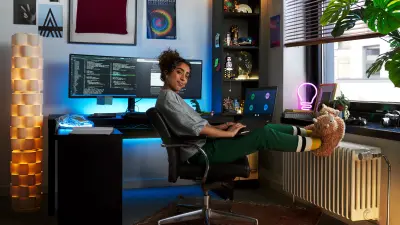Eine Frau sitzt in einer Home Office-Umgebung und lächelt in die Kamera.