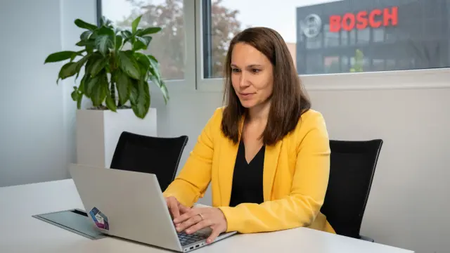 Isabel sitzt vor ihrem Laptop, im Hintergrund ist ein Bosch-Logo zu sehen.