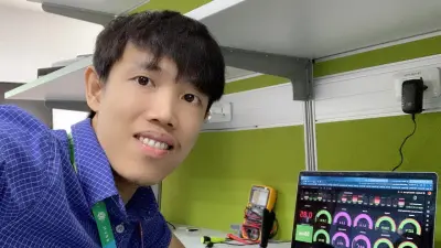 Selfie of Van Tuan Nguyen sitting in front of his laptop with analysis software open. He is wearing a blue checkered short sleeve shirt