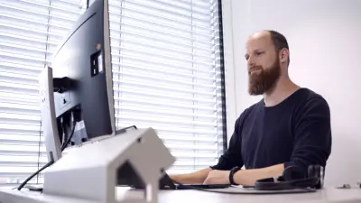 Stefan Essl sitzt an seinem Arbeitsplatz, den Blick auf den Computer-Bildschirm gerichtet. Er arbeitet konzentriert.