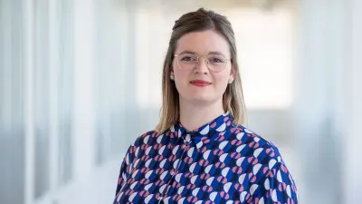Porträt von Tanja Maucher, die eine Brille und ein blau-gemustertes Oberteil trägt und in die Kamera blickt.