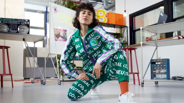 A woman is wearing a tailored suit with a all over print which says "CO2 neutral".