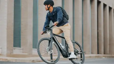 Ein Mann fährt in der Stadt auf einem eBike vor einem Gebäude um die Kurve.