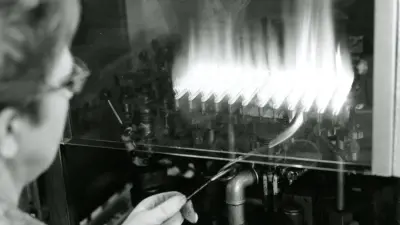 Mitarbeiterin in der Produktion prüft die Flammen einer Gastherme