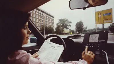 Woman at the steering wheel of a car entering the route code into a navigation system