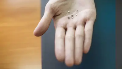 The surface of a right hand viewed from above, on which tiny metal objects are placed.