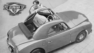 Frau an geöffneter Fahrertür eines Kleinwagens