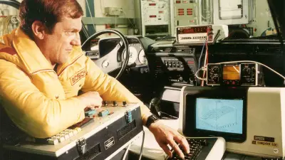 Mann im Auto, der einen Computer bedient.