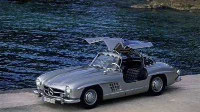 Sportliches silbernes Auto mit Wasser im Hintergrund.