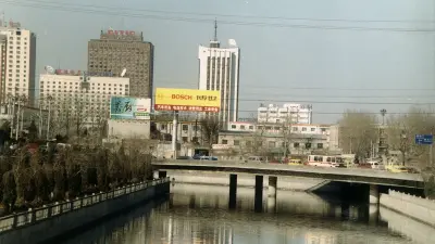 Fluss mit Brücke, dahinter Hochhäuser, großes gelbes Bosch-Reklameschild
