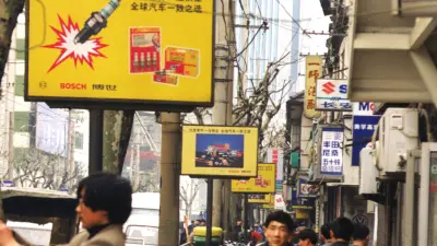 Bürgersteig in chinesischer Stadt mit Fußgängern, Zweirädern und Bosch-Werbung