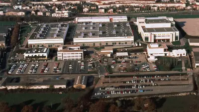 Aerial view of the factory complex, residential buildings in the background.