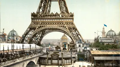 View of the lower part of the Eiffel Tower with exhibition building and bridge over the Seine.
