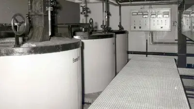 View of a room with three large boilers, in the background on the wall the associated control panel
