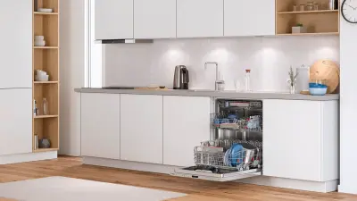 Modern kitchen unit with open dishwasher containing dishes