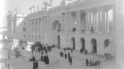 Black and white photograph of the entrance to a trade fair building, visitors in front of it