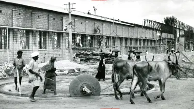 Ox-drawn wheel and people at construction site.
