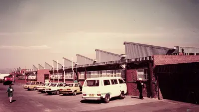 Blick auf einen Industriebau mit davor geparkten Fahrzeugen