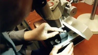 A man’s hand holds a nozzle under a microscope