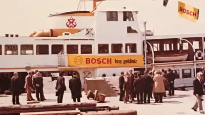 A ship is in port. It carries a banner with the inscription "Bosch hos geldiniz" (English "Welcome")