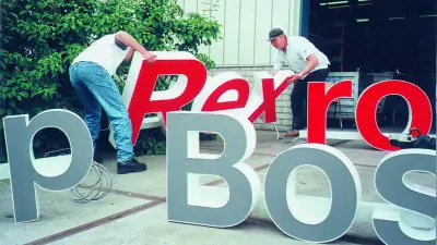 Zwei Männer mit Teilen einer großen Leuchtschrift „Rexroth“ und „Bosch“.