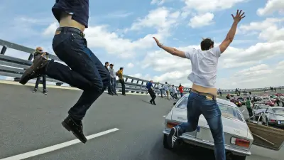 Menschen springen mit begeistert erhobenen Armen auf eine Fahrbahn