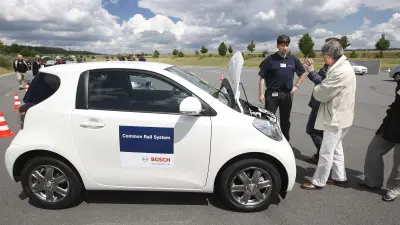 Four people standing around a white vehicle.