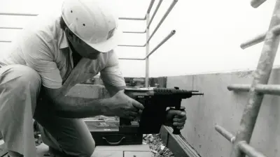 Mann, der mit Akku-Bohrhammer in die Wand bohrt