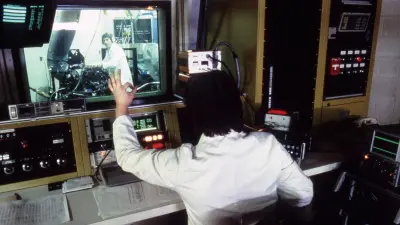 A man at the computer, a man behind the window at the car in a workshop