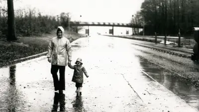 A father and his young daughter take a walk on an empty freeway