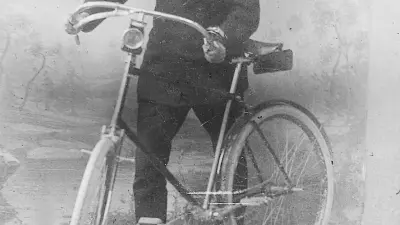 Vorderseite seiner Visitenkarte. Robert Bosch mit seinem ersten Geschäftsfahrzeug, einem Fahrrad. (1890)