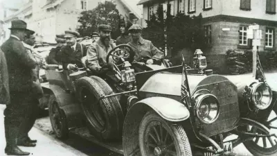 Robert Bosch sits at the wheel of a large, open-top car with five passengers.