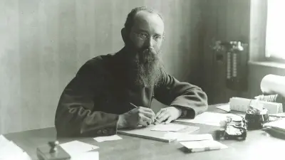 Robert Bosch is sitting at his desk, with a telephone next to him on the wall.
