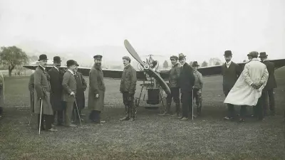 Robert Bosch and aviator Hans Grade stand with a group of spectators in front of an airplane