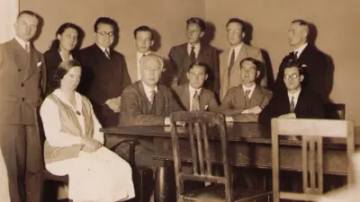 Group photo of six men and one woman standing and one woman and four men sitting in front.