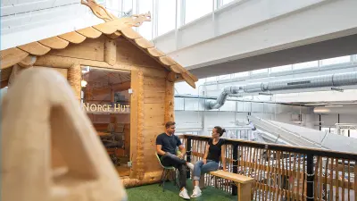 Meeting in front of a wooden hut inside a factory builing